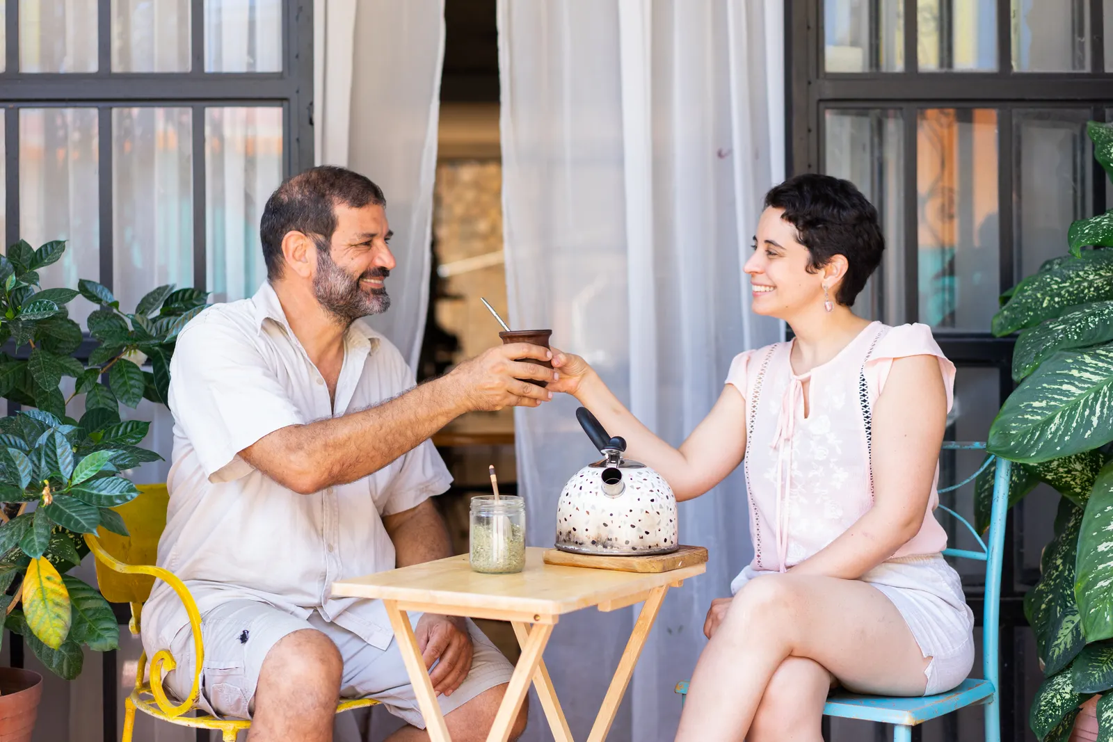 Dos compañeros comparten un mate en un patio soleado